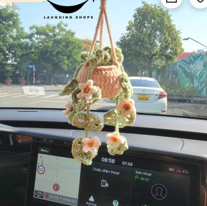 Green and white knitted wool car plant ornament hanging from a rope