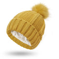 Women's knitted beanie hat with faux fur pom pom in wine red, showing satin lining interior.