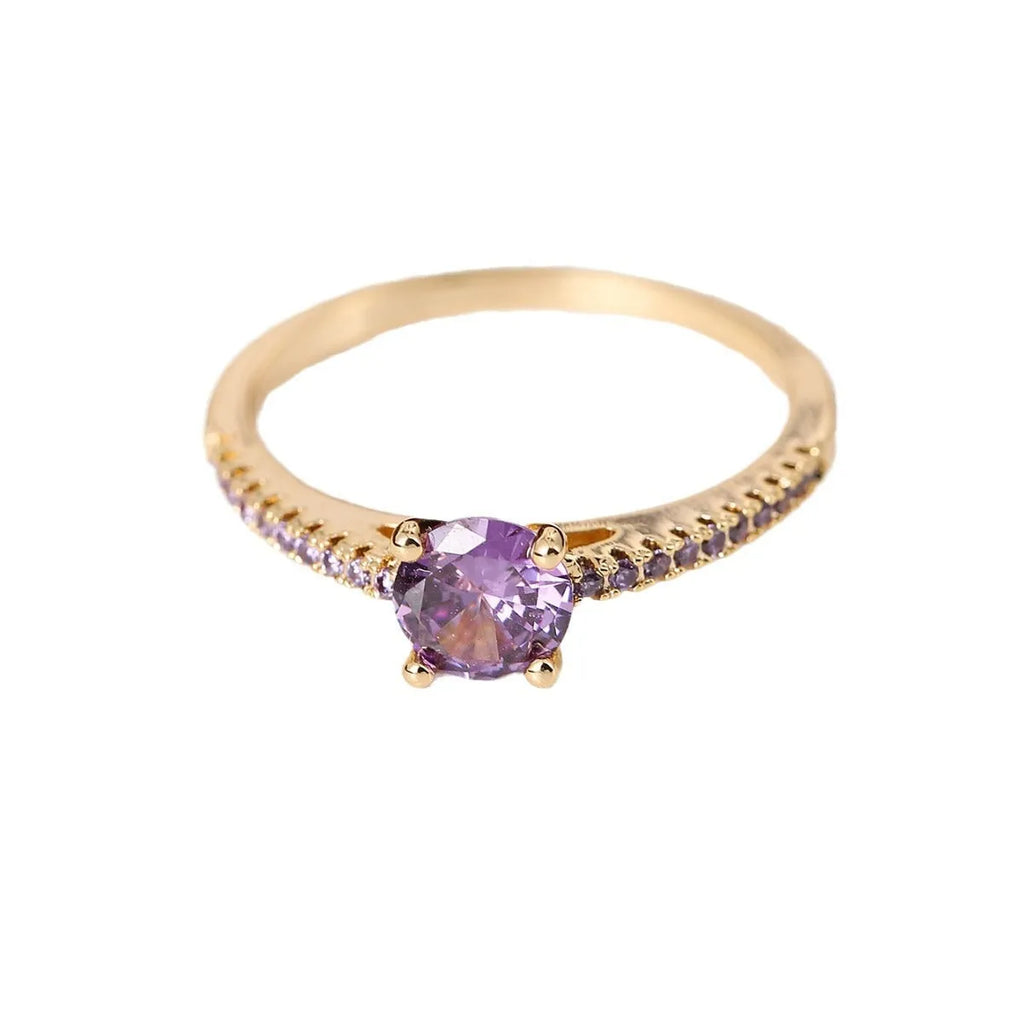 A hexagonal geometric ring with a zircon stone, shown in a gun black and rose red electroplated finish on a finger.