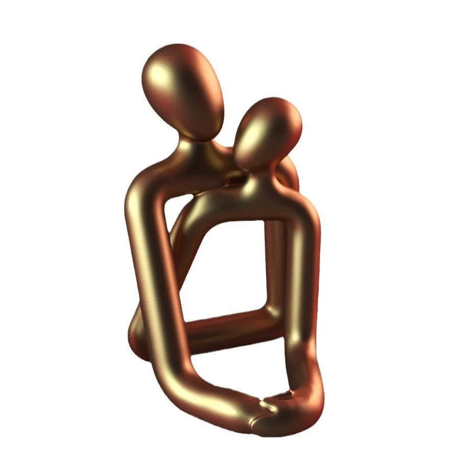 Modern minimalist resin statue of a couple in milky white or gold finish on a wooden surface.