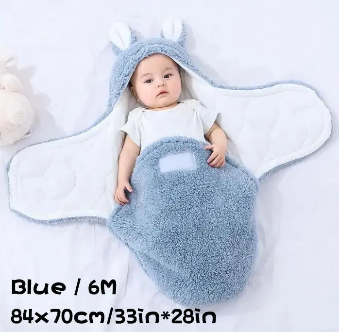 Baby wearing a grey adjustable fleece swaddle sleep sack with velcro wings