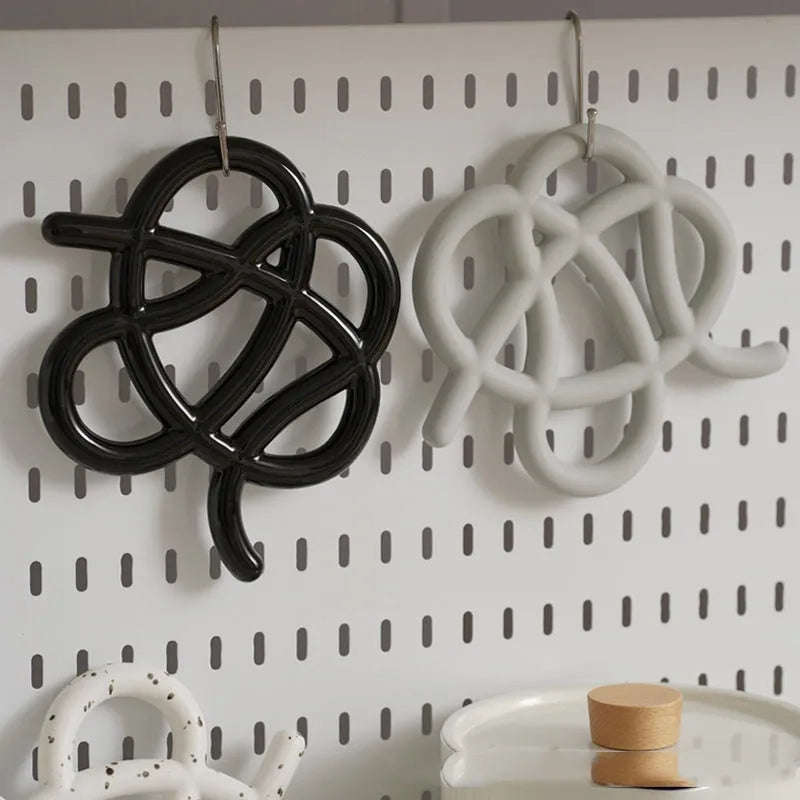 Modern irregular-shaped ceramic heat proof mat in grey protecting a wooden dining table from a hot pan.