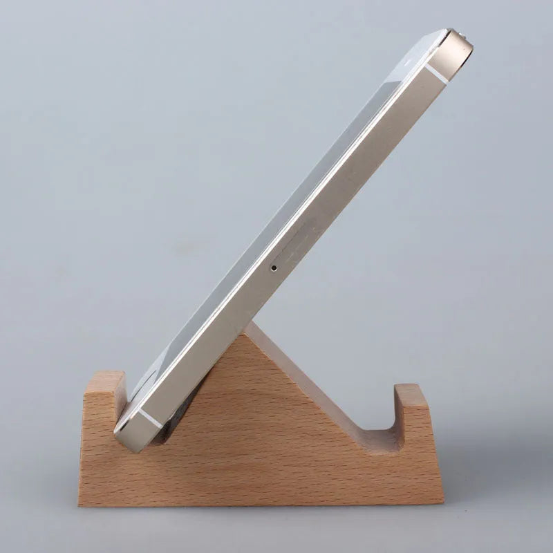 Solid beech wood mobile phone stand with a resin cow figurine and a slot for holding coins on a wooden desk.