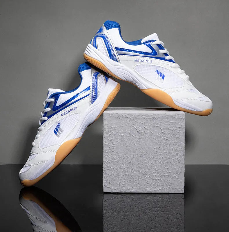 White table tennis sneakers with red trim, showing round toe and lace-up front.