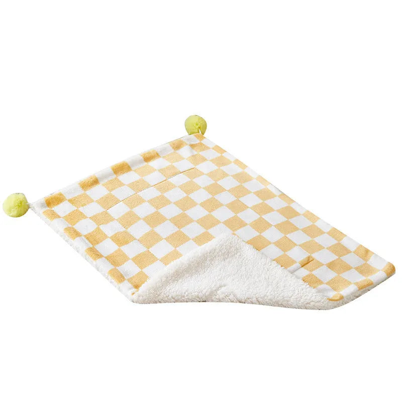 Plush pet blanket with plaid pattern and fur ball decoration for cats and dogs on sofa