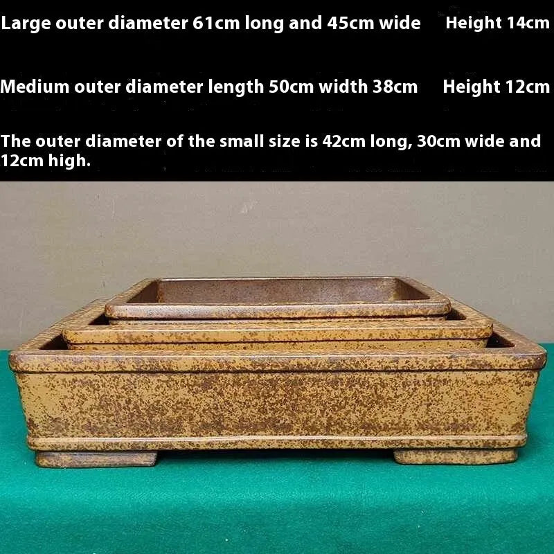 Straight-sided shallow rectangular flower pot made from unglazed Yixing purple sand clay, on a wooden surface.