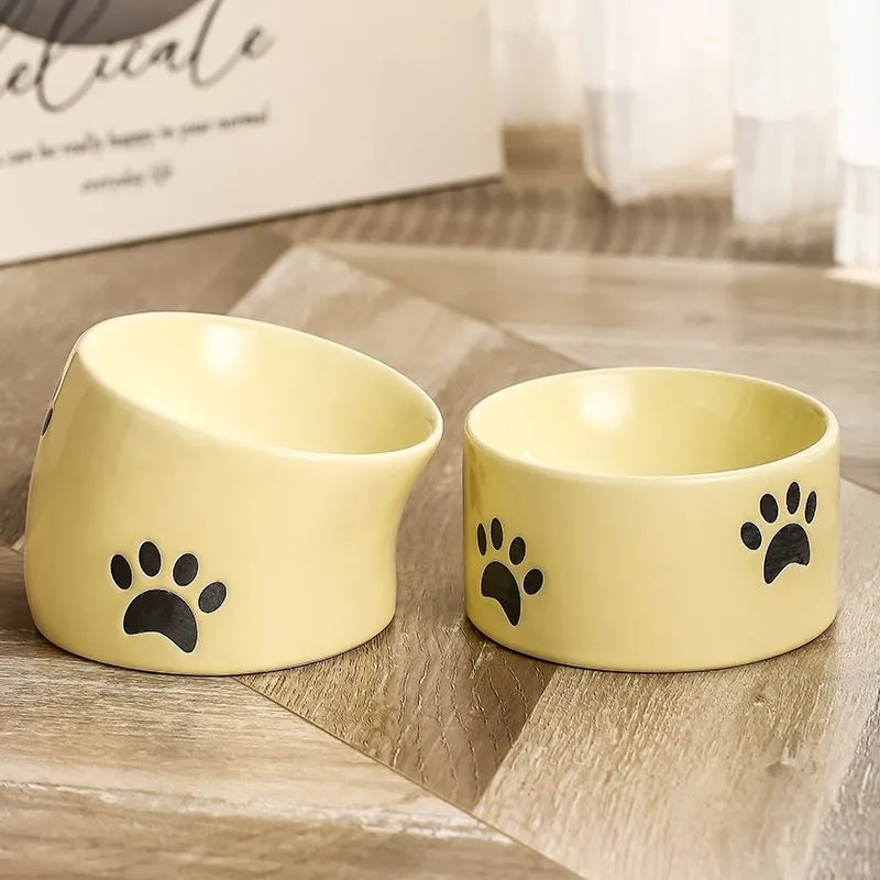 Ceramic cat food bowl with high foot base in a cat's paw print design
