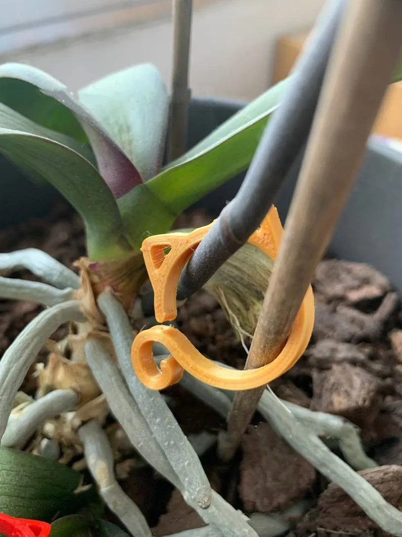 Small red cat-shaped plastic clip for plants on a white background.