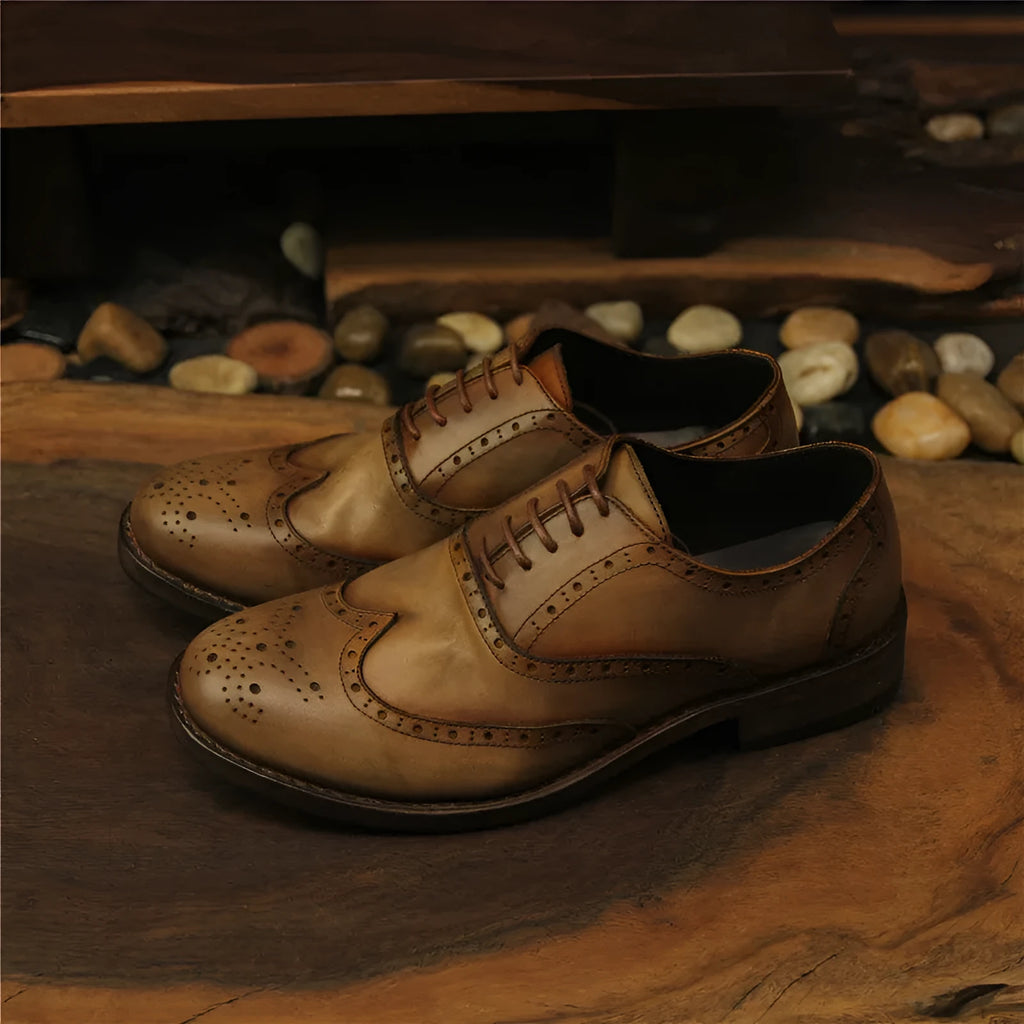 Light brown men's distressed leather lace-up shoes with engraved detailing and round toe on a neutral background.