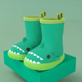 Shark brand children's green rain boots with a dinosaur graphic, showing medium height and plastic construction.