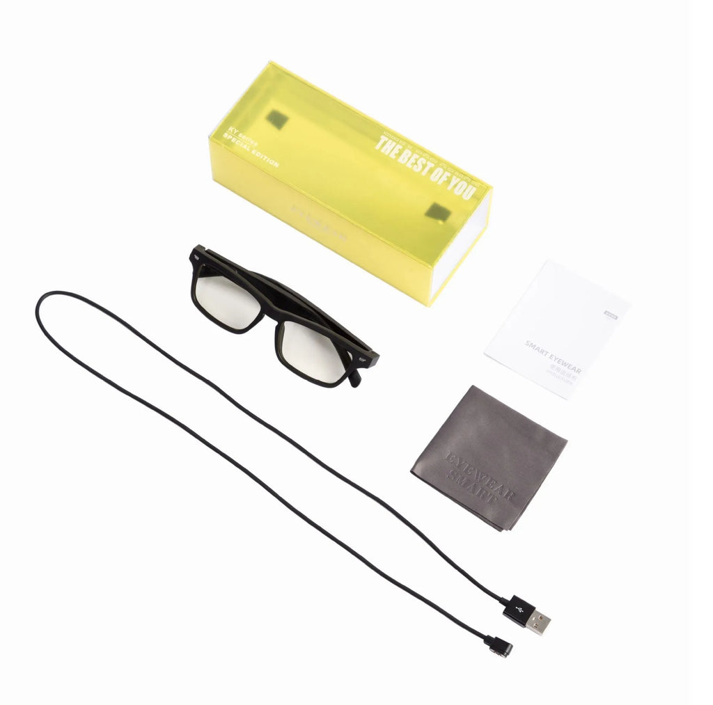 Black smart glasses with Bluetooth speakers and tinted UV-protection lenses on a table.