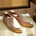 British handmade brown leather men's loafers with a flat TPR sole on a wooden surface.