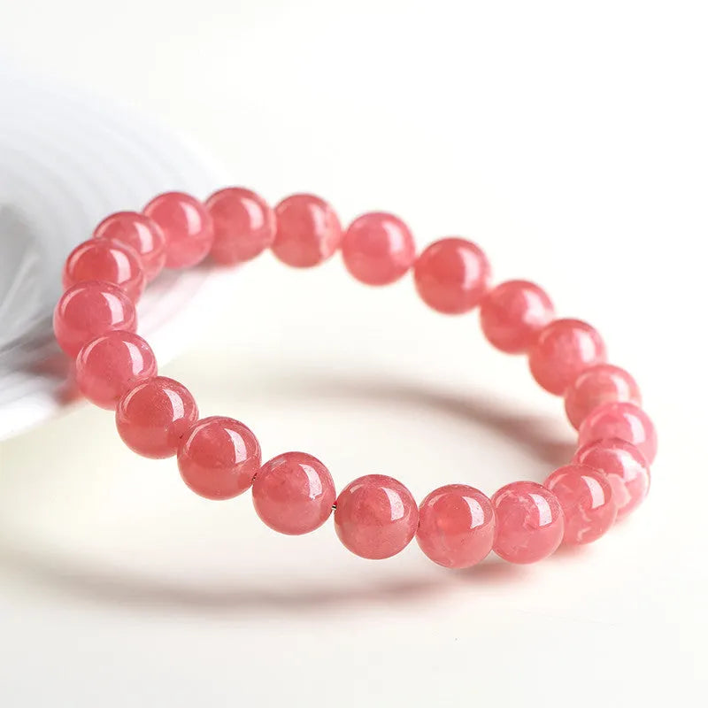 Close-up of a red rhodochrosite crystal bracelet with geometric beads and a Longevity Lock clasp.