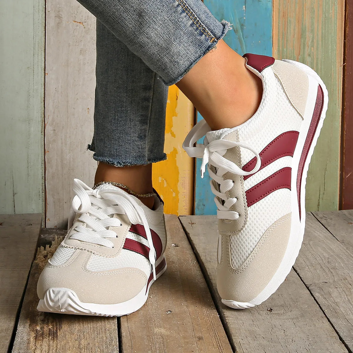 Wine red Cortez retro sneaker with cross straps, mesh lining, and flat rubber sole.