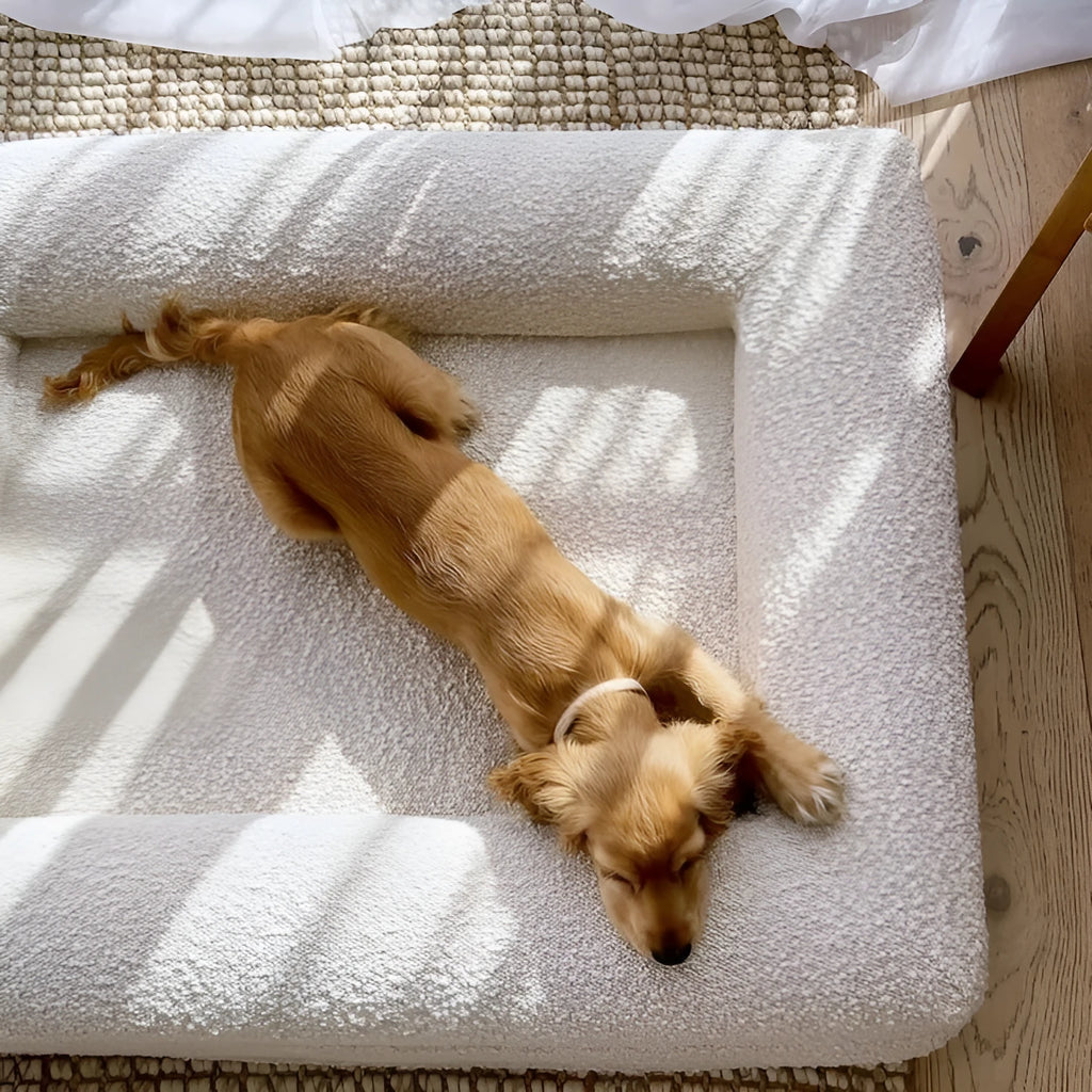 Beige rectangular cloth dog bed nest with raised sides, shown in medium size on a wooden floor.