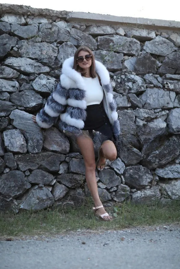 A woman wearing a loose-fitting artificial fur coat with a hood, in a street fashion style.