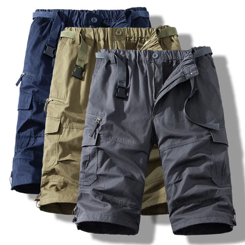Men's cotton cropped overalls in army green, shown in a casual summer setting.