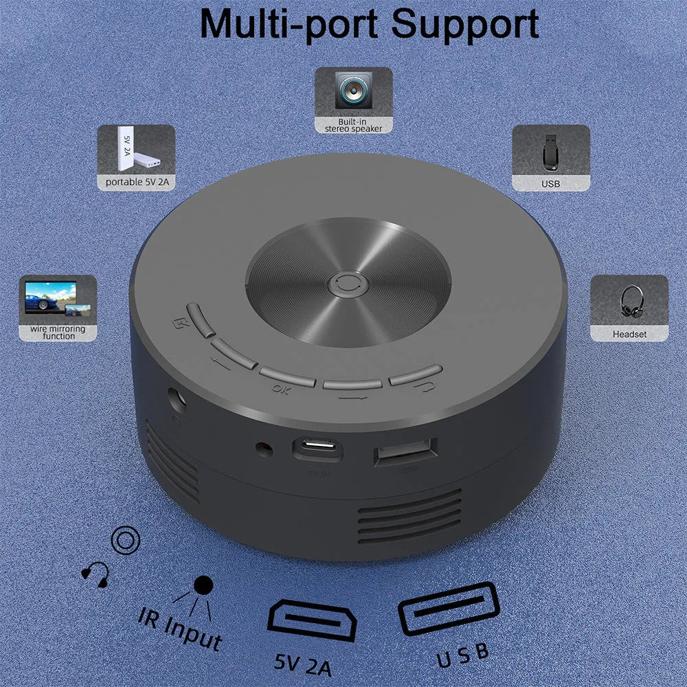 Black portable mini projector for children next to a mobile phone on a table.