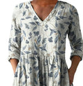 A woman wearing a loose-fitting floral print dress with 3/4 ruffle sleeves and a wide waist.