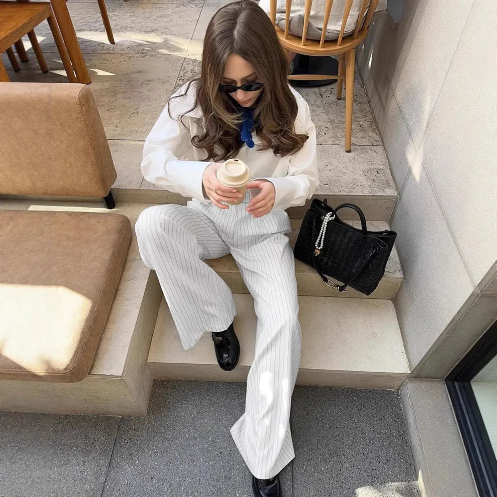 White striped wide-leg women's trousers with a front zip on a hanger.