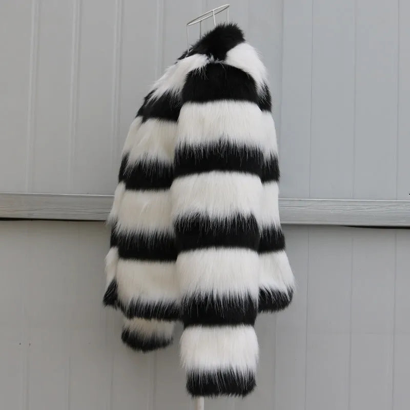 Long-sleeved black and white striped faux fur jacket for women on a grey background.