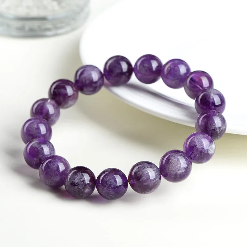 Natural feather amethyst crystal bracelet with scattered geometry beads and Ruyi element on a wrist.