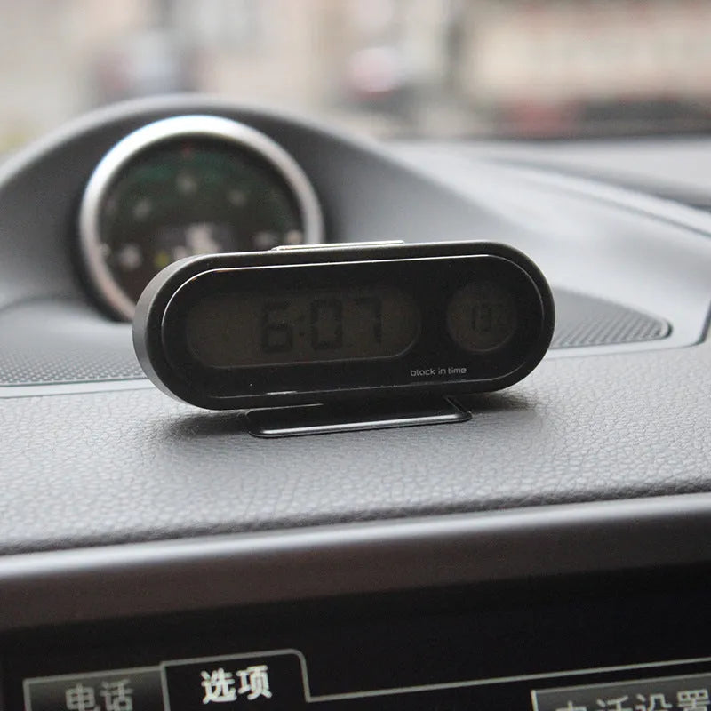Black electronic car clock and thermometer with LED digital display on an adjustable dashboard bracket.
