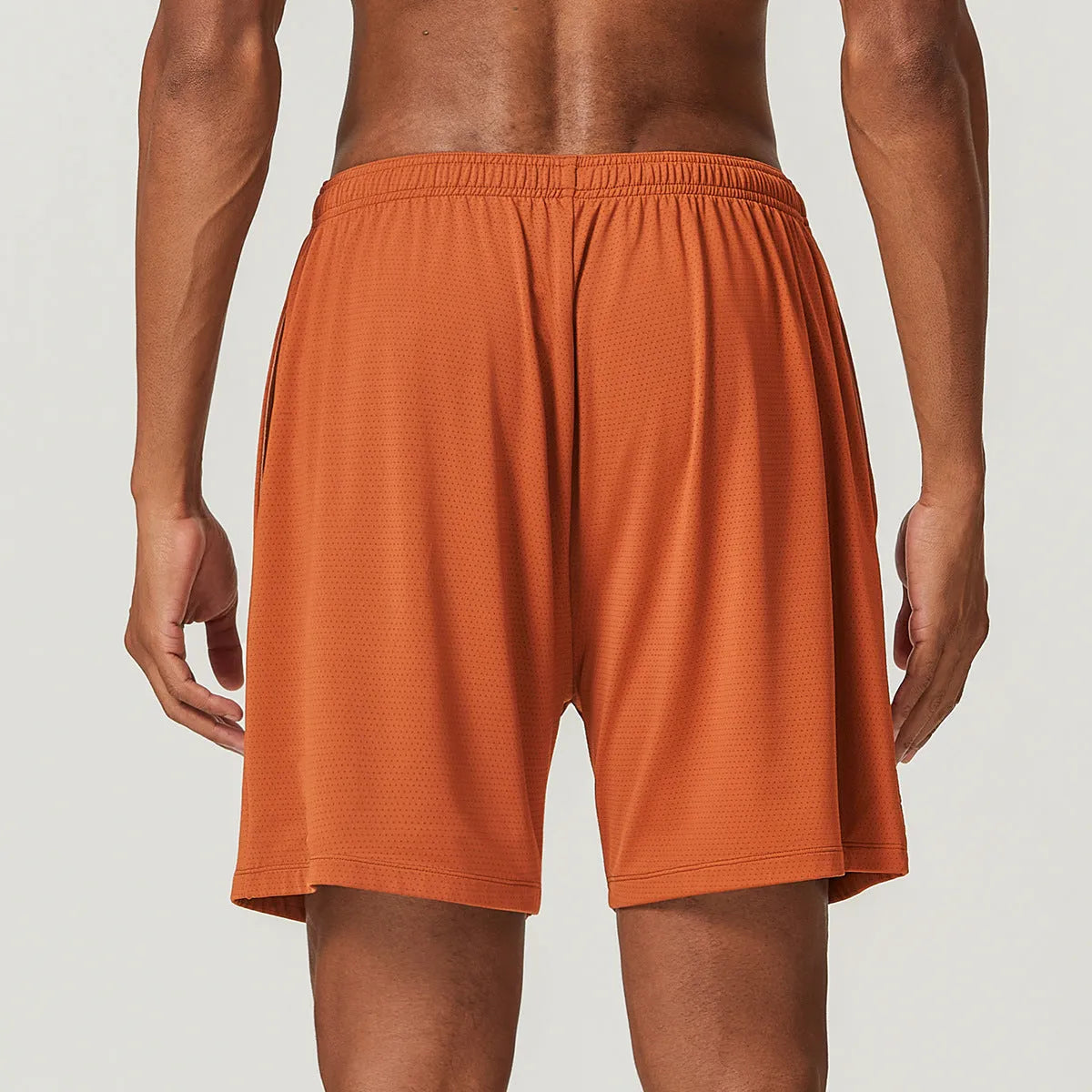 Men's quick-drying double-layer running shorts in brick red colour on a mid waist fit model.