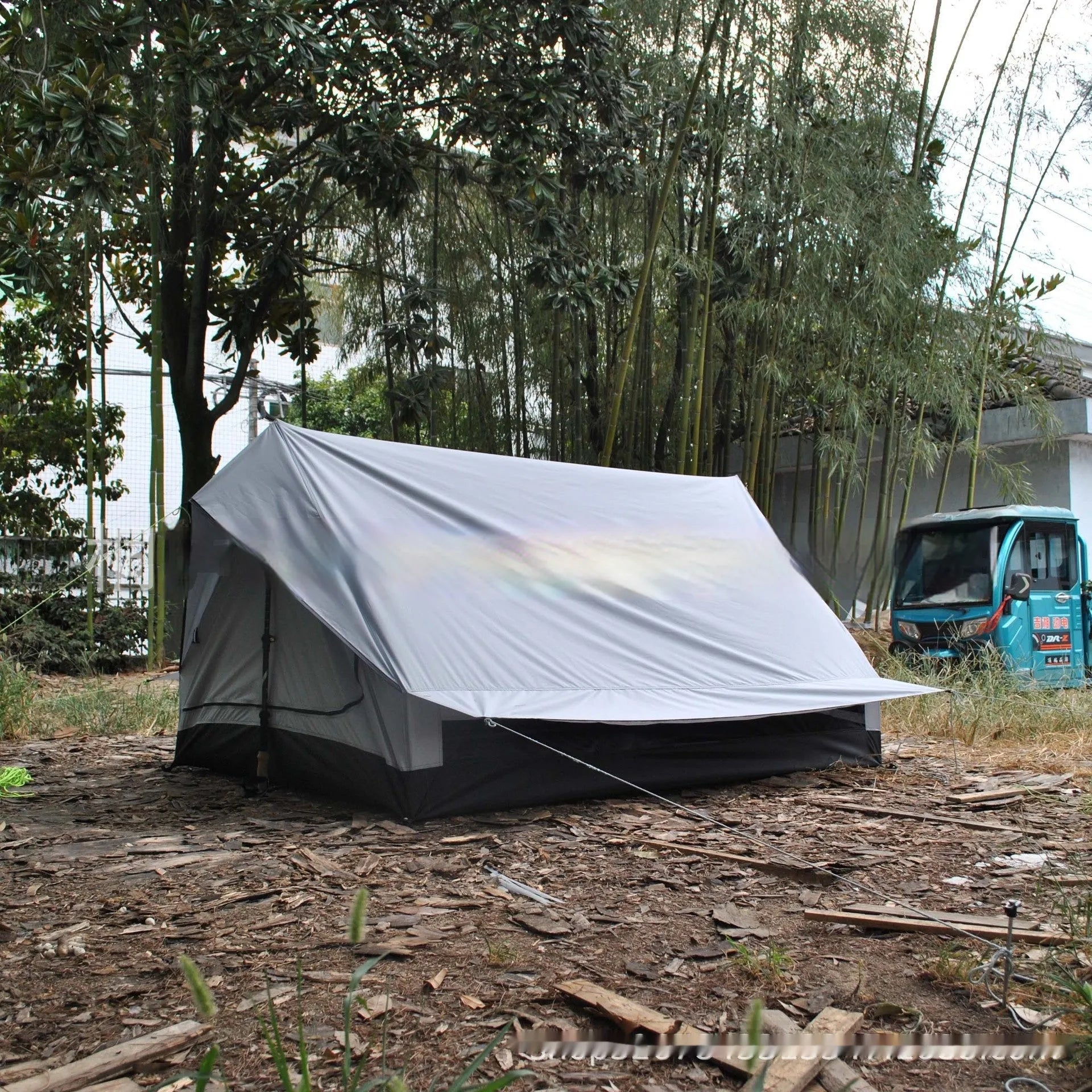 Brown A-Line pole-free cabin tent set up in a forest, showing its spacious interior for 2-3 people.