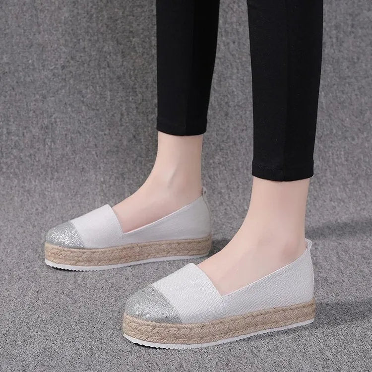 Plus size beige canvas slip-on flat shoes with a round toe on a white background.