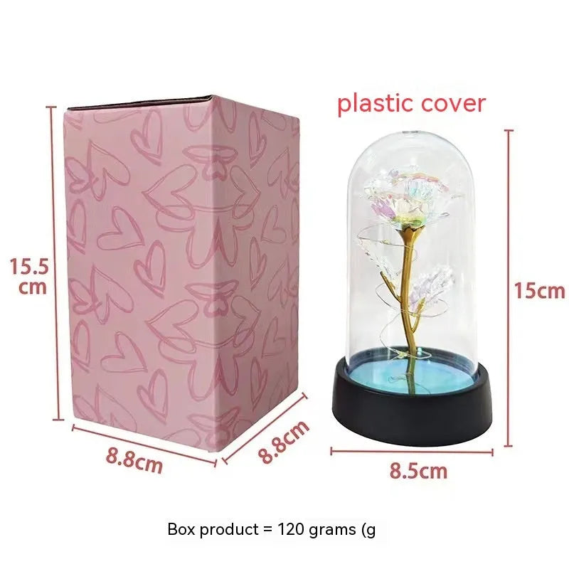 Small glass cover night lamp with plastic flowers, showing coloured LED light options on a black base.