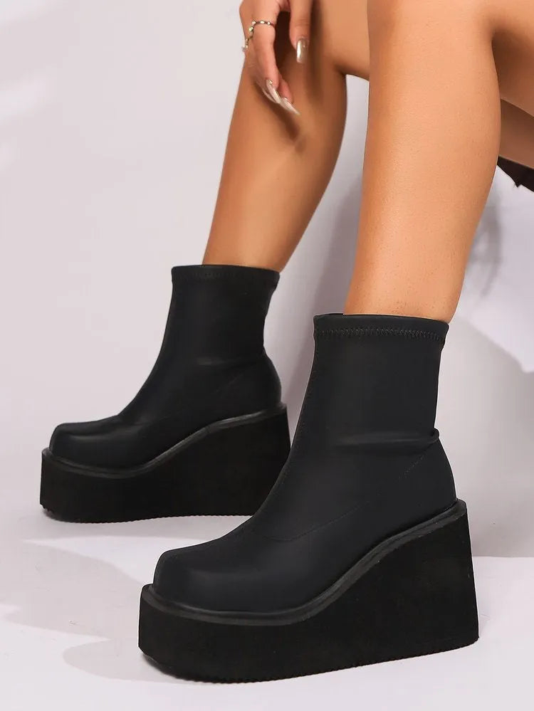 Women's black wedge-heel ankle boot with a round toe and waterproof platform sole on a plain background.