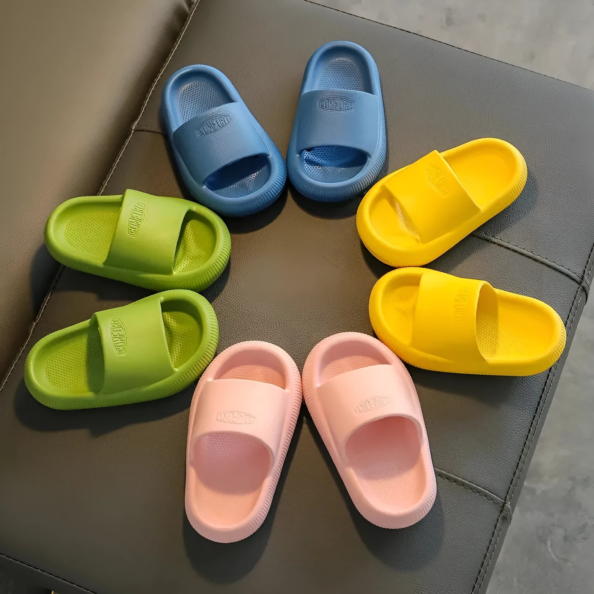 Bright coloured EVA children's house slippers with thick, textured non-slip soles on a wooden floor.