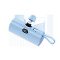 Compact capsule-shaped wireless power bank with digital display and integrated plug, shown in multiple colours.