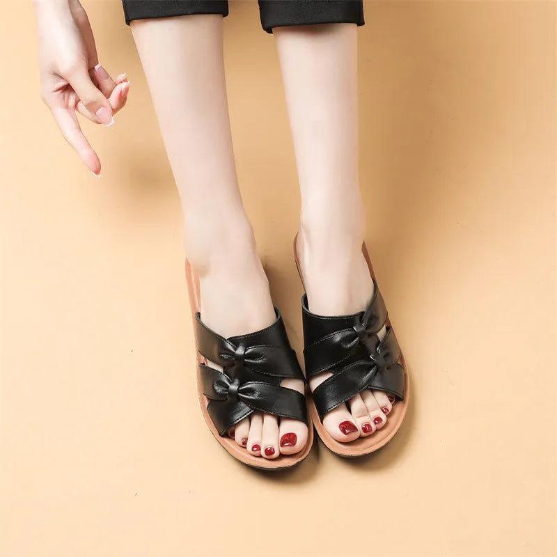 Women's beige cowhide slippers with a soft sole on a plain background.