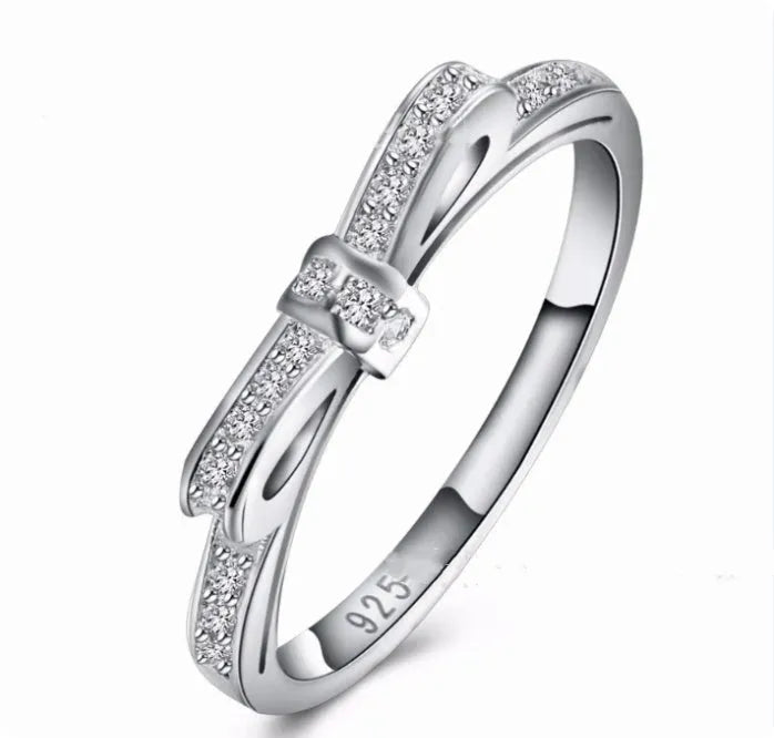 Silver electroplated sterling silver ring with a wide bow design set with clear zircon crystals.