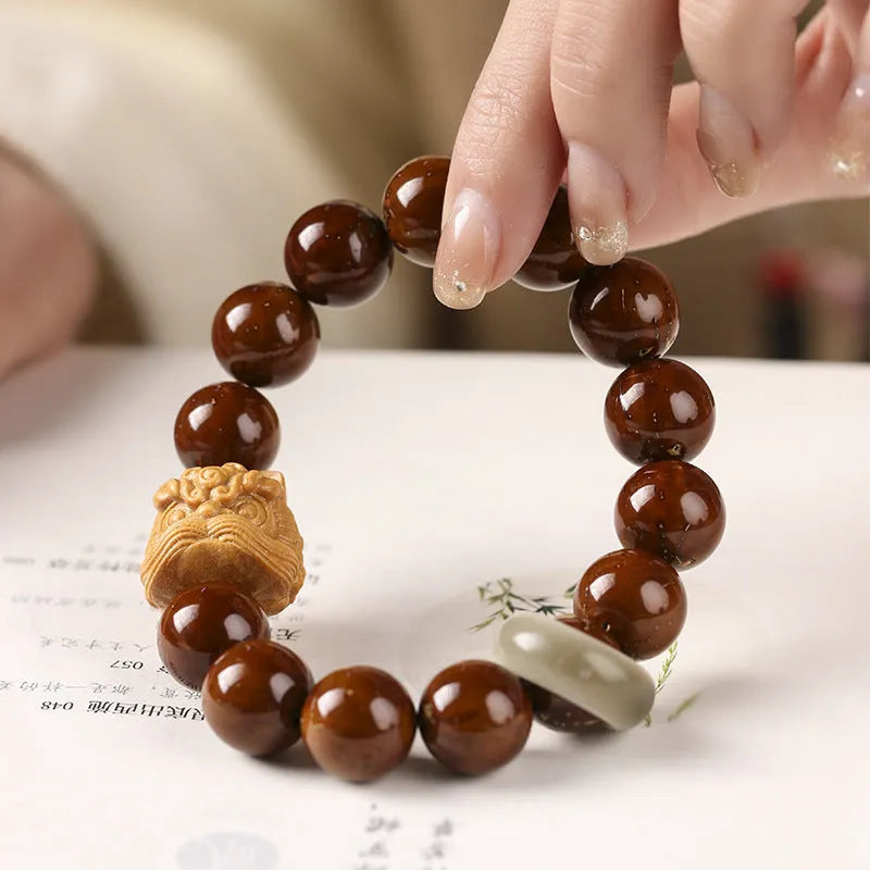 Hand-woven bracelet with 13mm round beads showing lion design in ivory nut, bodhi or sandalwood style
