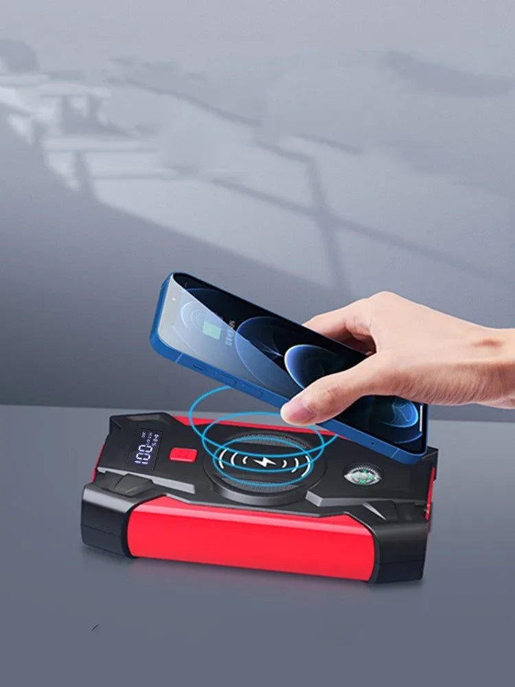 Red car emergency jump starter power pack with digital display and strong jumper clamps.