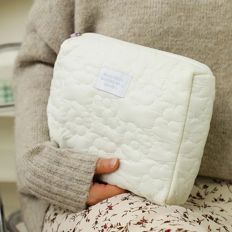 Silk quilted cosmetic storage bag for women shown in a candy colour, with a quilted pattern and zip closure.