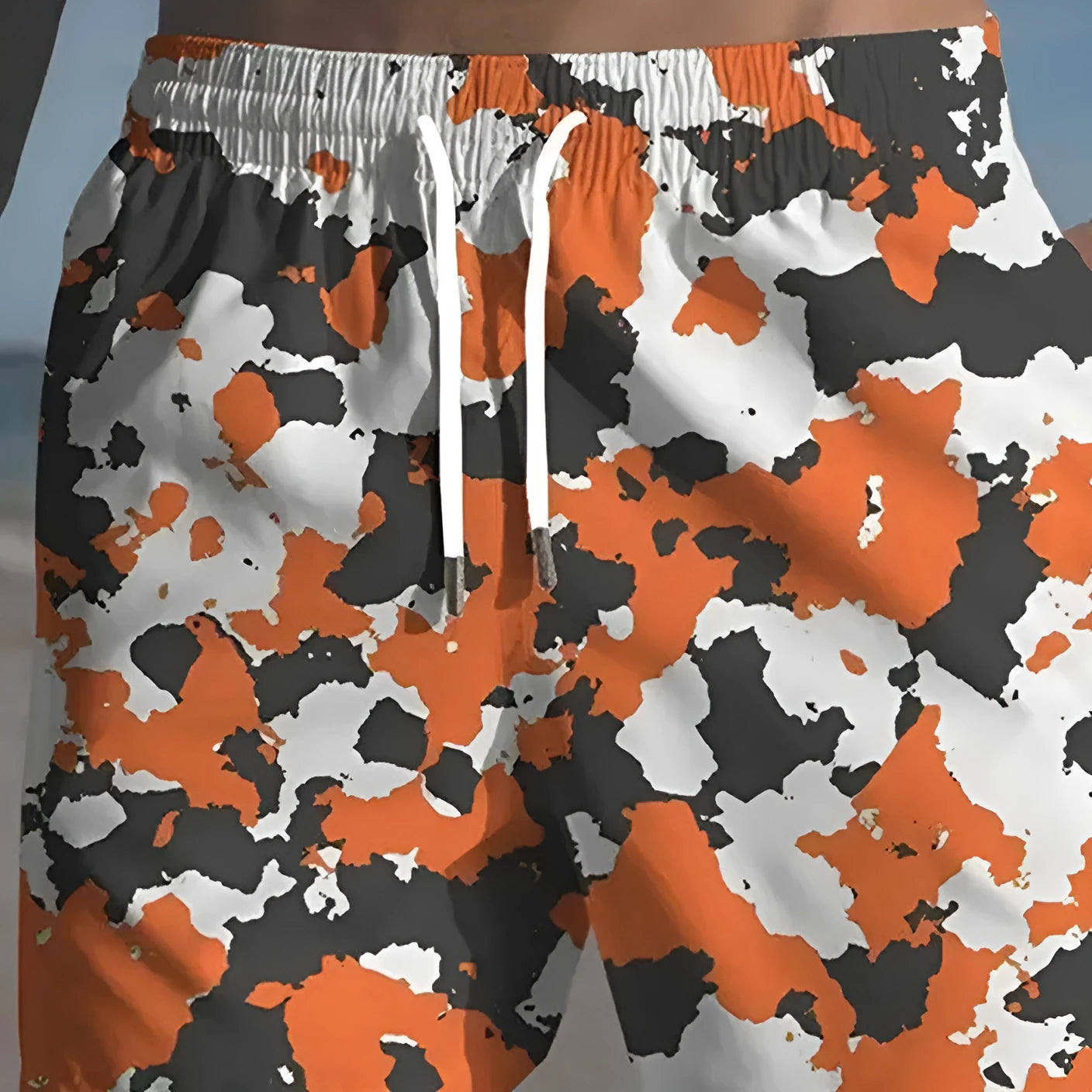 Man wearing coloured print polyester beach shorts with an elastic waistband for summer travel.