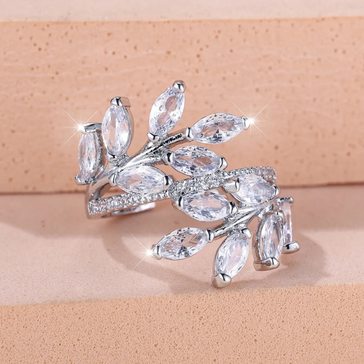 Adjustable copper leaf-shaped ring with sparkling zircon stones in rose gold and platinum finishes.