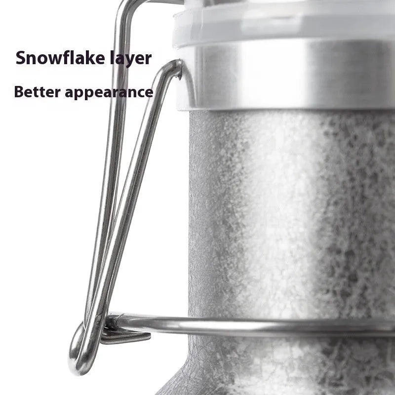 Large stainless steel outdoor thermal pot with a handle, shown in a natural setting.