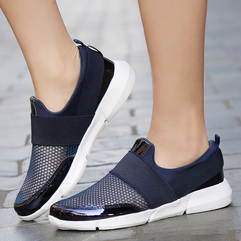Women's low-top blue casual sneakers with mesh material and a PU midsole on a hard floor.