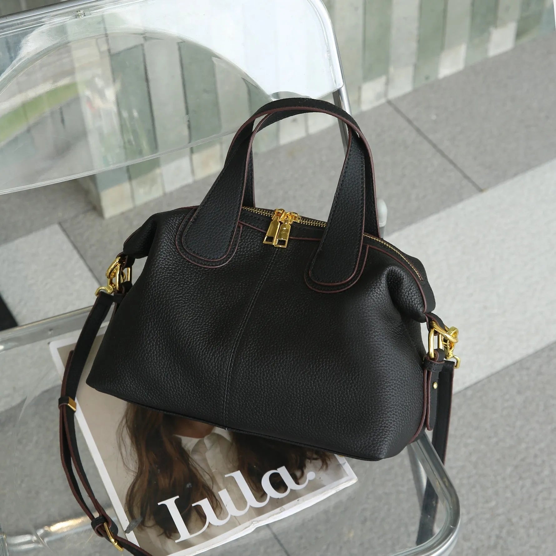 Black genuine leather women's cross-body shoulder bag with square shape and cross-body strap.