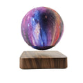 Walnut-coloured magnetic levitation base with floating galaxy-patterned moon lamp illuminated in dark setting