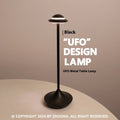 Modern gold UFO-shaped metal desk lamp with touch-sensitive base on a wooden table.