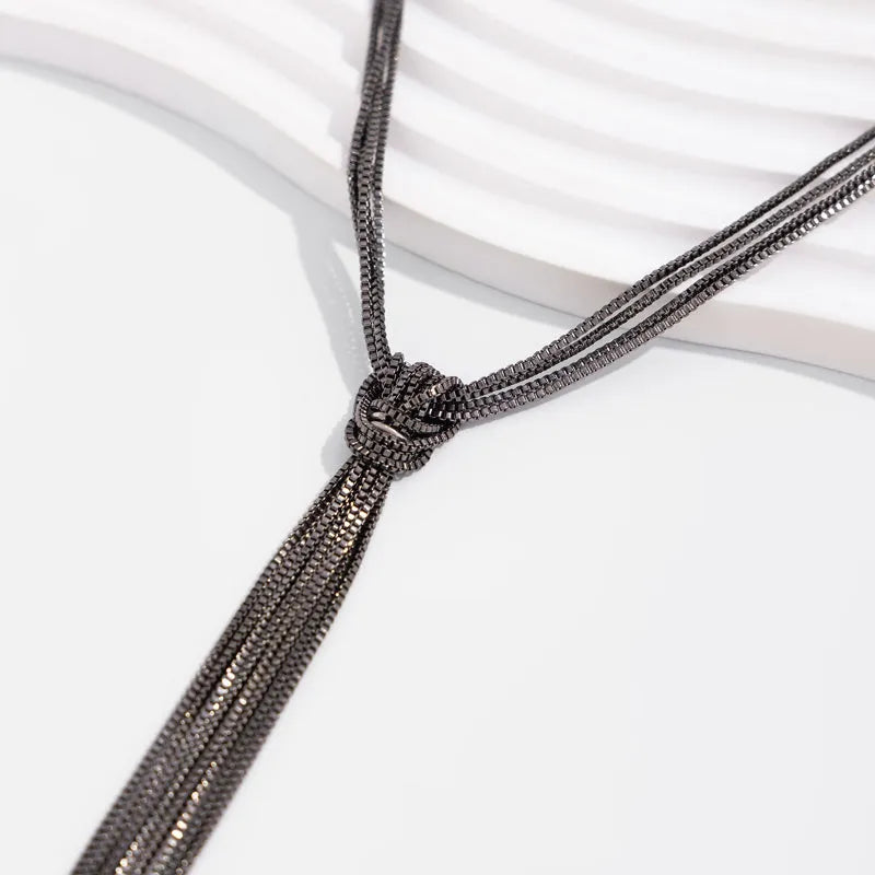 Simple Y-shaped metal tassel necklace in gold finish on a woman, with matching earrings, minimalist style for commuting wear