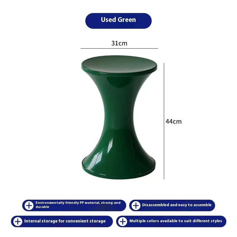 Green plastic hourglass-style shoe changing stool on a wooden floor.