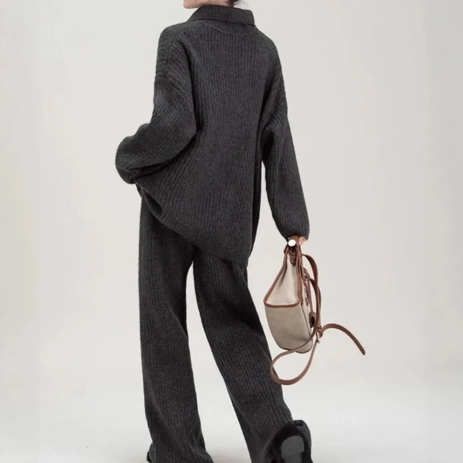 Women's beige knitted two-piece suit set showing V-neck top and straight-leg trousers on a hanger.