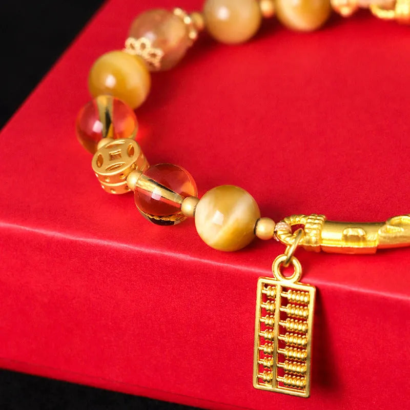 Close-up of a women's beaded bracelet with diamond-shaped tigereye and citrine stones and copper details.
